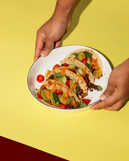 Smokin Hot Peanut Butter Tacos auf einem weißen Teller werden auf einen gelben Tisch gestellt.