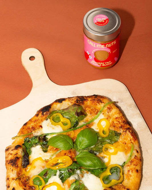 Smokin Hot Peanut Butter Pizza auf einem Holzbrett und einem Glas Smokin Hot Peanut Butter auf braunem Hintergrund.