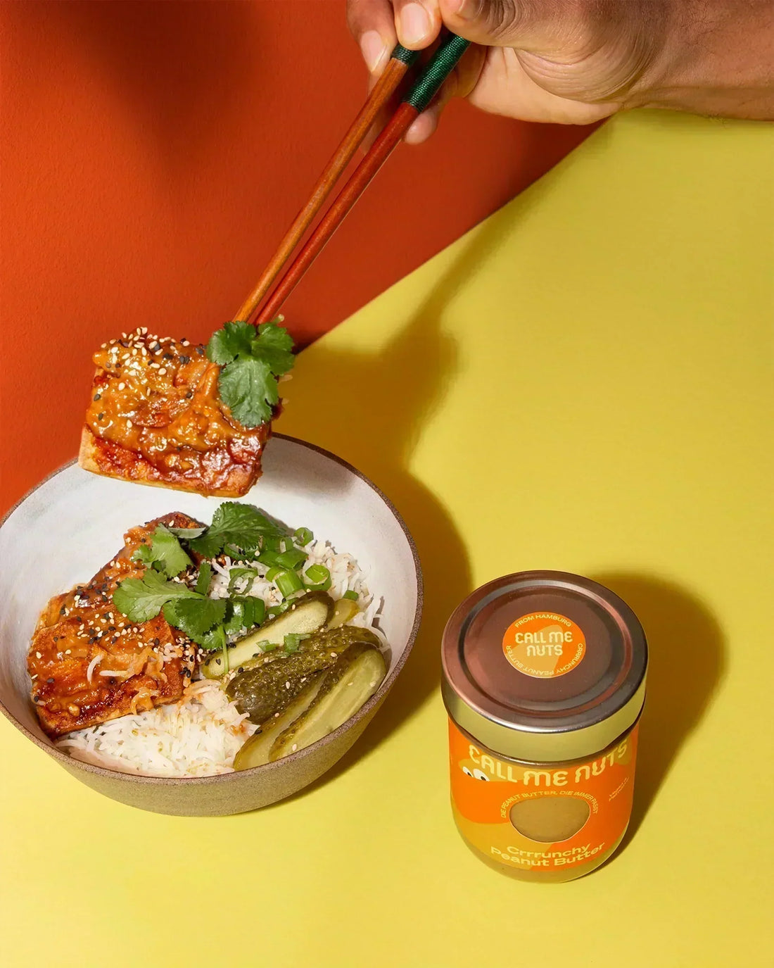 Mit Crrrunchy Peanut Butter marinierter Tofu auf Reis und Gewürzgurke in einer großen Schüssel.