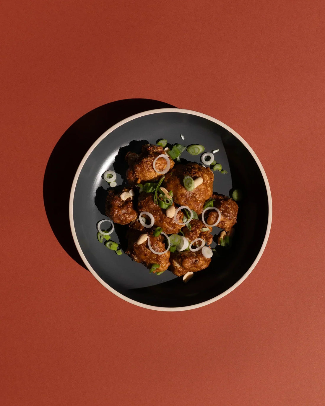 Teller mit Smokin' Hot Blumenkohl Wings auf dunkelrotem Hintergrund