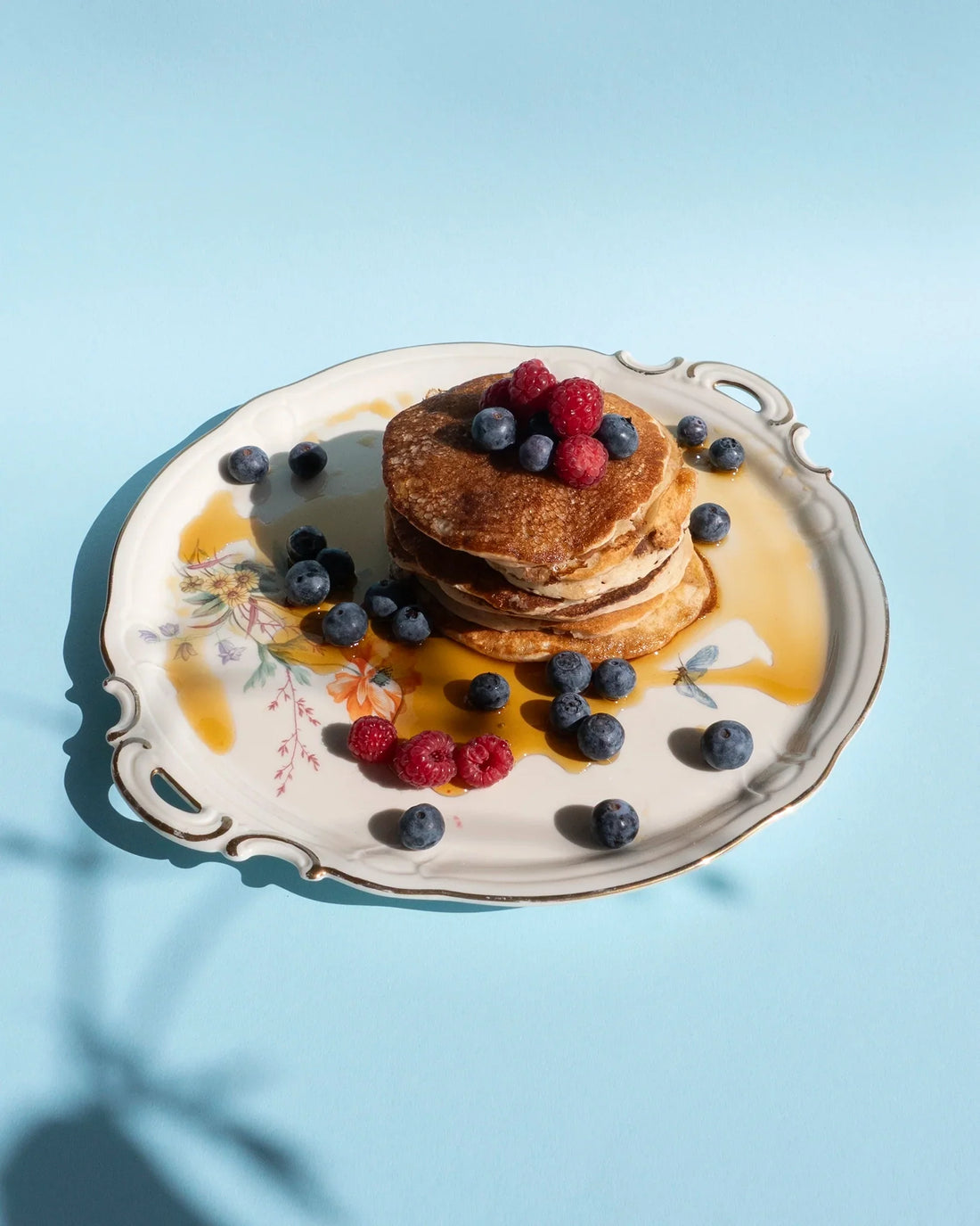 Teller mit einem Stapel Smoooth Peanut Butter Pancakes mit Ahornsirup und frischen Beeren