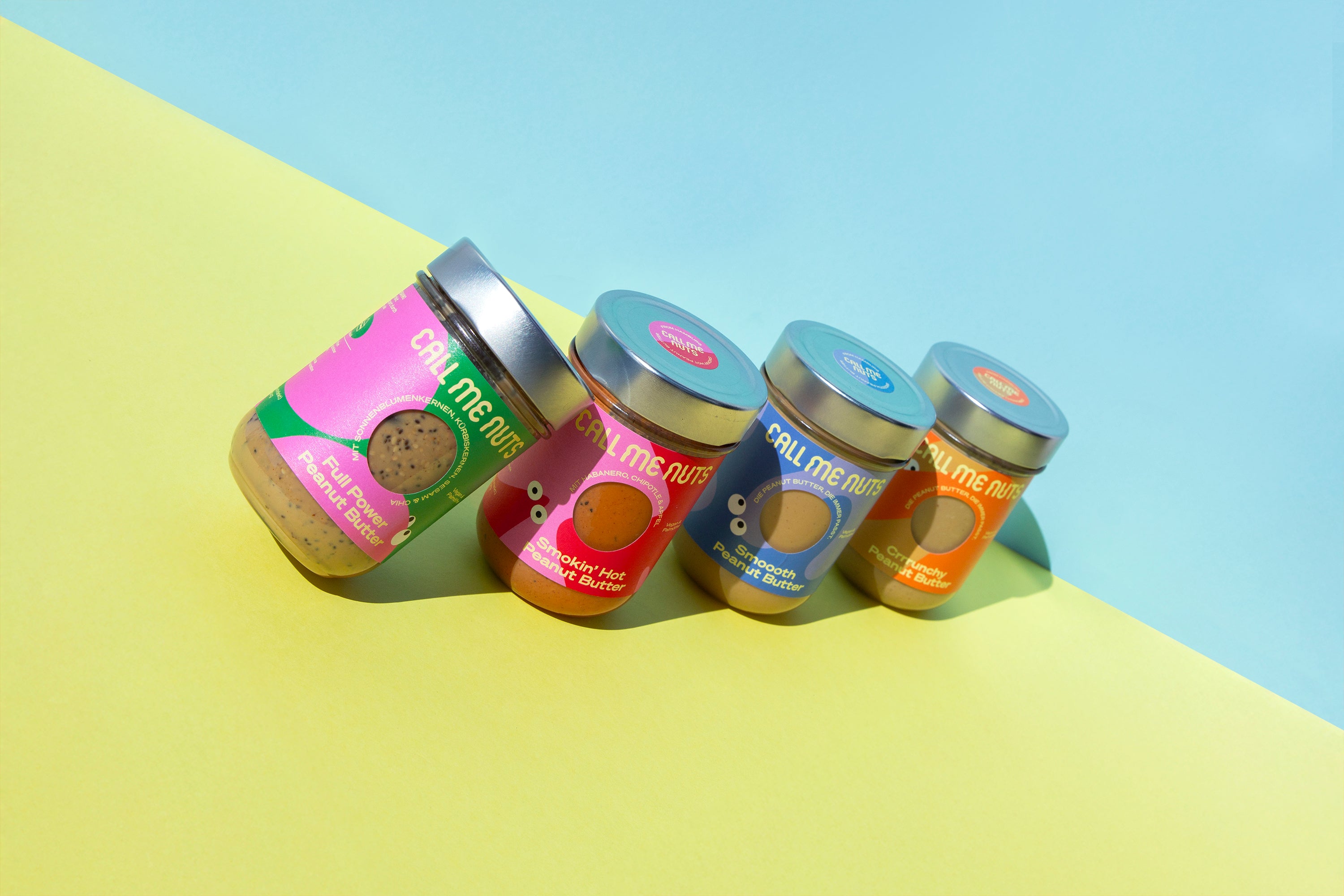 Alle Peanut Butter Gläser in einer Reihe vor gelb-blauem Hintergrund